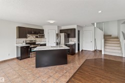 Kitchen with dark wood cabinetry, stainless steel appliances, a center island with a white countertop, and tile flooring - 