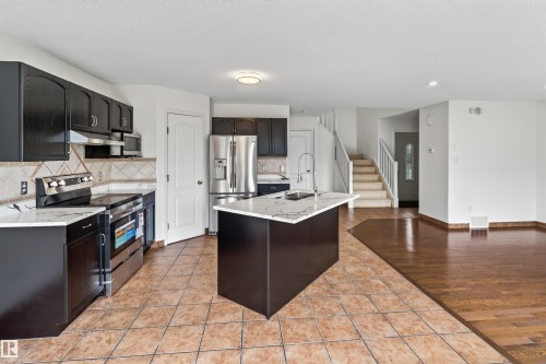 Modern kitchen with black cabinetry, stainless steel appliances, and an island featuring a white countertop - 1707 37A Avenue Nw, Edmonton, AB - Indoor Photo Showing Kitchen With Double Sink With Upgraded Kitchen