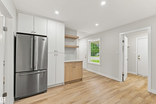 Wood-finish flooring throughout, complemented by white cabinetry and stainless steel appliance - #21 9375 172 St Nw, Edmonton, AB - Indoor Photo Showing Other Room