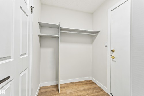 Wood-finish flooring, built-in shelving, and white paneled doors - #21 9375 172 St Nw, Edmonton, AB - Indoor With Storage