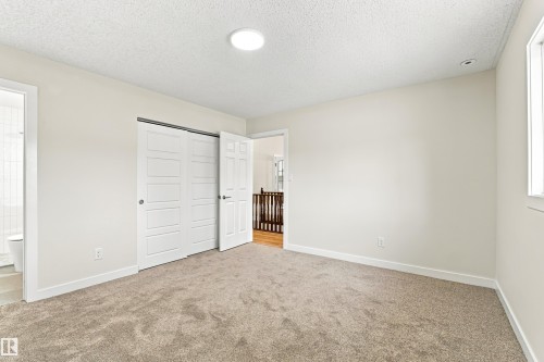 Neutral wall paint, plush carpet flooring, recessed lighting, and a window with white trim - #21 9375 172 St Nw, Edmonton, AB - Indoor Photo Showing Other Room