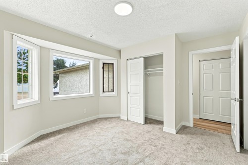 Recessed bay window, light grey carpeting, white trim, sliding closet doors, and a flush mount ceiling light - #21 9375 172 St Nw, Edmonton, AB - Indoor Photo Showing Other Room