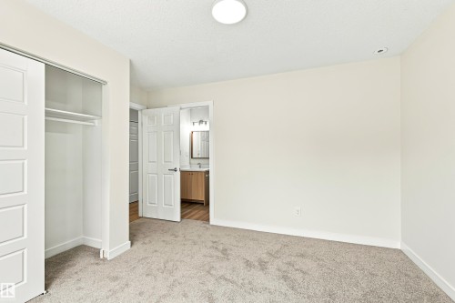 Plush carpeting, sliding closet doors, built-in closet shelving, overhead flush mount lighting, and a recessed ceiling light - #21 9375 172 St Nw, Edmonton, AB - Indoor Photo Showing Other Room