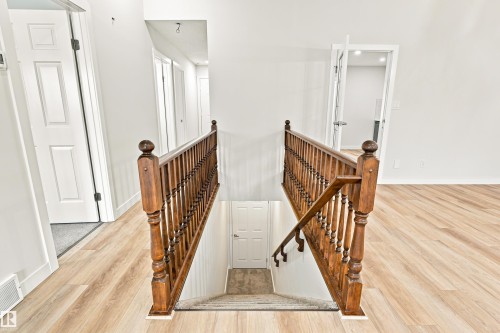 Wood-finish flooring, white walls, and a wood banister with turned spindles - #21 9375 172 St Nw, Edmonton, AB - Indoor Photo Showing Other Room