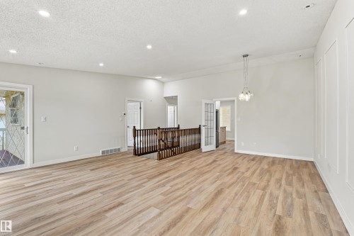 Wood-finish flooring throughout, recessed ceiling lighting, decorative wall paneling, and a contemporary chandelier - #21 9375 172 St Nw, Edmonton, AB - Indoor Photo Showing Other Room