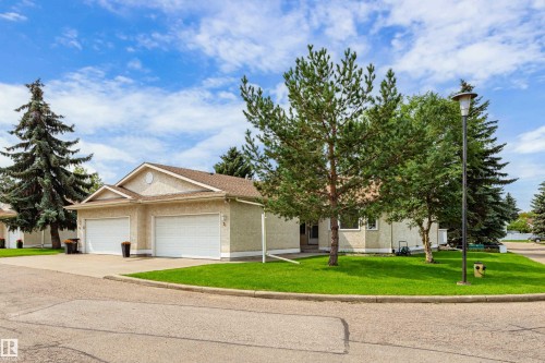 Stucco exterior with an attached two-car garage, concrete driveway, and mature landscaping - #21 9375 172 St Nw, Edmonton, AB - Outdoor