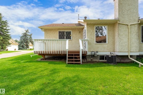 Expansive lawn with a raised wood deck, leading to a stucco exterior - #21 9375 172 St Nw, Edmonton, AB - Outdoor With Deck Patio Veranda