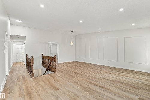 Spacious interior featuring wood-finish flooring, recessed lighting, and decorative wall paneling - #21 9375 172 St Nw, Edmonton, AB - Indoor Photo Showing Other Room