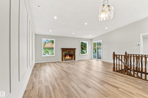 Wood-finish flooring, recessed lighting, and a wood-mantel fireplace - #21 9375 172 St Nw, Edmonton, AB - Indoor Photo Showing Other Room With Fireplace
