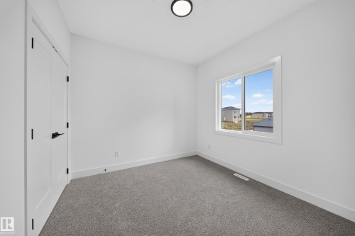 Neutral wall colors, grey carpeting, a large window, and matte black door hardware - 222 Black Stone Drive Drive, Leduc, AB - Indoor Photo Showing Other Room