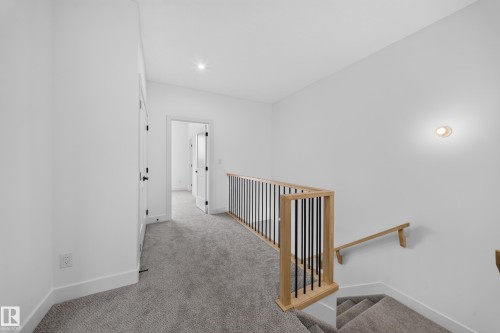 Gray carpeted landing with a wood and black metal railing, white walls, and recessed lighting - 222 Black Stone Drive Drive, Leduc, AB - Indoor Photo Showing Other Room