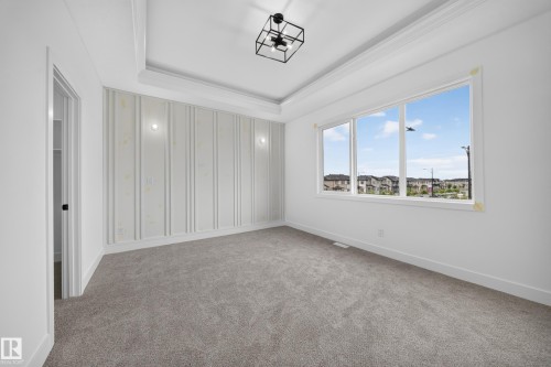 Tray ceiling with crown molding, accent wall with vertical paneling, recessed lighting, and large windows - 222 Black Stone Drive Drive, Leduc, AB - Indoor Photo Showing Other Room