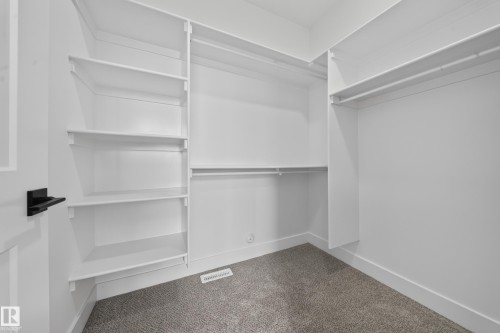 Custom built-in shelving, white finish cabinetry, integrated hanging rods, and neutral carpet - 222 Black Stone Drive Drive, Leduc, AB - Indoor With Storage
