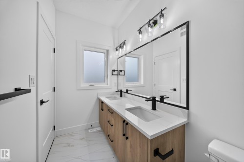 Double vanity with integrated sinks and matte black fixtures, set against a full-width framed mirror - 222 Black Stone Drive Drive, Leduc, AB - Indoor Photo Showing Bathroom