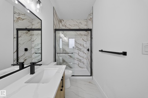 Walk-in shower with a glass enclosure, white and gray veined wall and floor tile, wood-finish vanity with an integrated sink, and matte black fixtures - 222 Black Stone Drive Drive, Leduc, AB - Indoor