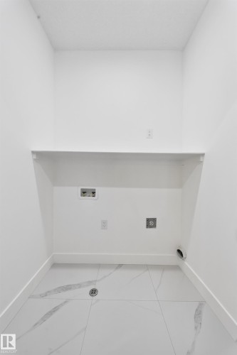 Laundry area with a built-in shelf, white walls, and large format floor tiling - 222 Black Stone Drive Drive, Leduc, AB - Indoor Photo Showing Other Room