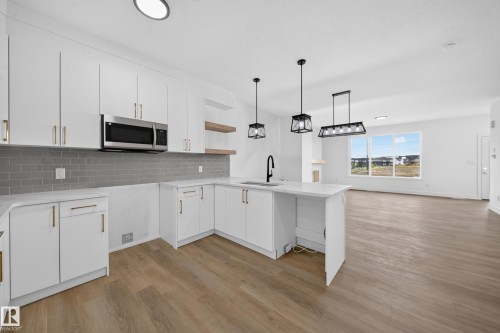 Modern kitchen featuring white cabinetry, a gray subway tile backsplash, white countertops, and wood-finish flooring - 222 Black Stone Drive Drive, Leduc, AB - Indoor Photo Showing Kitchen With Upgraded Kitchen