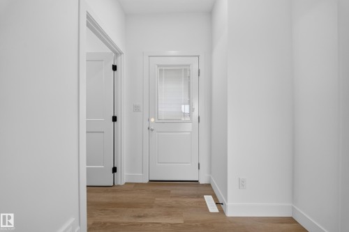 Entryway featuring wood-finish flooring, white paneled doors with black hardware, and a door with an inset glass panel - 222 Black Stone Drive Drive, Leduc, AB - Indoor Photo Showing Other Room