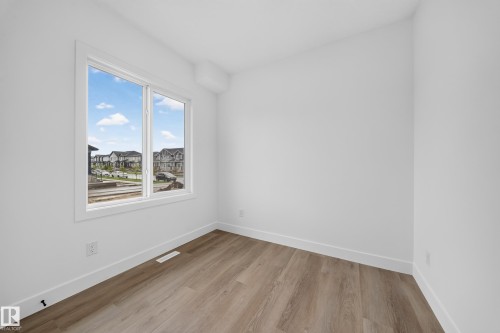 Bright interior featuring a large window, white walls, and wood-finish flooring - 222 Black Stone Drive Drive, Leduc, AB - Indoor Photo Showing Other Room