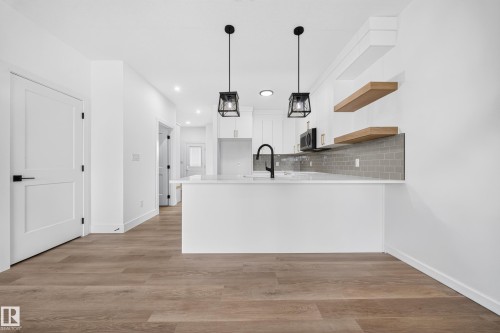 Modern kitchen with white shaker cabinetry, white countertops, subway tile backsplash, and wood-finish flooring - 222 Black Stone Drive Drive, Leduc, AB - Indoor