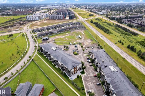 Aerial perspective showcasing multiple residential buildings, paved roadways, and extensive green spaces - #227 148 Ebbers Bv Nw, Edmonton, AB - Outdoor With View