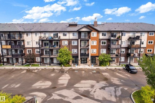 Multi-story building featuring balconies with black railings, a dark shingle roof, and a combination of light and dark-toned exterior siding - #227 148 Ebbers Bv Nw, Edmonton, AB - Outdoor With Balcony With Facade