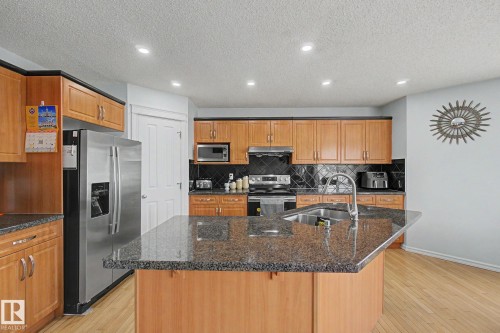 Kitchen featuring wood cabinetry, stainless steel appliances, a center island with a sink, and recessed lighting - 3236 21 Street Nw, Edmonton, AB - Indoor Photo Showing Kitchen With Double Sink