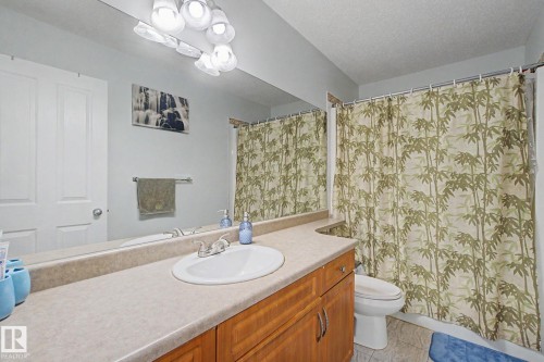 Bathroom vanity with a light-colored countertop, an undermount sink, and a two-door wood-finish cabinet - 3236 21 Street Nw, Edmonton, AB - Indoor Photo Showing Bathroom