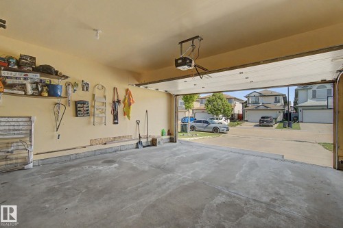 Concrete flooring, automatic garage door opener, integrated shelving, and wall-mounted storage - 3236 21 Street Nw, Edmonton, AB - Indoor Photo Showing Garage