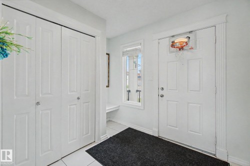 White paneled entry door with fluted trim, white window, and built-in bench - 3236 21 Street Nw, Edmonton, AB - Indoor Photo Showing Other Room