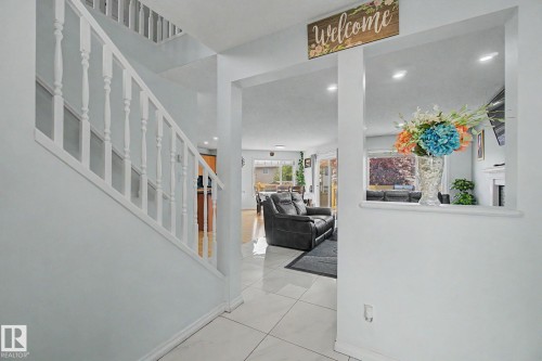 White balustrade staircase, recessed lighting, tile flooring, and a half-wall architectural feature - 3236 21 Street Nw, Edmonton, AB - Indoor Photo Showing Other Room