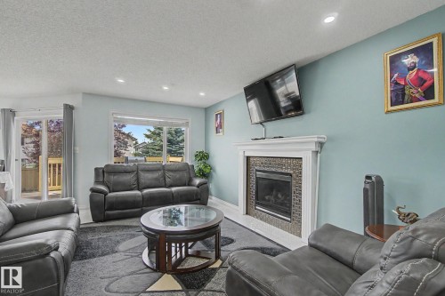 Living area with recessed lighting, a built-in fireplace featuring a tile surround and white mantel, and a large window - 3236 21 Street Nw, Edmonton, AB - Indoor Photo Showing Living Room With Fireplace