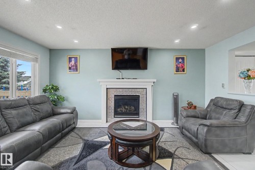 Recessed ceiling lighting, fireplace with tile surround, white mantel, light-colored walls, and large window - 3236 21 Street Nw, Edmonton, AB - Indoor Photo Showing Living Room With Fireplace