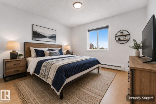 Light wood-finish flooring, a contemporary ceiling light fixture, and a large window with white trim - #416 2305 35A Av Nw, Edmonton, AB - Indoor Photo Showing Bedroom