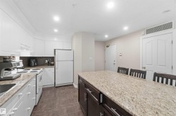 Kitchen featuring white cabinetry, a built-in range, a double-door refrigerator, and a center island with a stone-finish countertop - 
