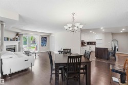 Wood-finish flooring, white fireplace with mantle, sliding glass patio door, recessed lighting, and kitchen island with seating - 