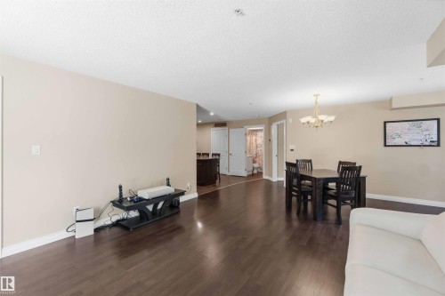 Expansive living area with wood-finish flooring, neutral wall tones, and recessed lighting - #104 10221 111 St Nw, Edmonton, AB - Indoor