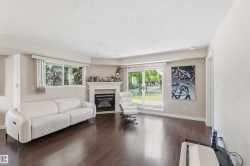 Living area with wood-finish flooring, a built-in fireplace, multiple windows with blinds, and a sliding glass door - 
