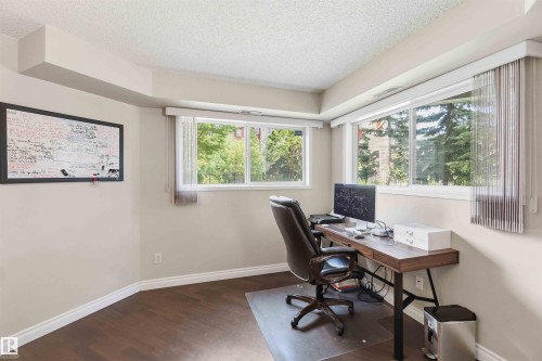 Wood-finish flooring with white trim, multiple windows, and neutral wall paint - #104 10221 111 St Nw, Edmonton, AB - Indoor Photo Showing Office