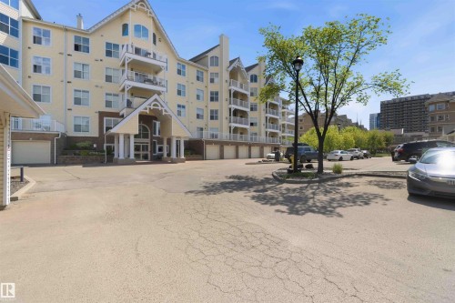 Multi-story residential building featuring a prominent front entrance with columns, multiple balconies, and integrated garage doors - #104 10221 111 St Nw, Edmonton, AB - Outdoor With Facade