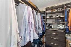 Built-in closet system featuring multiple hanging rods, open shelving, integrated drawers with horizontal hardware, and a glass-topped display shelf - 