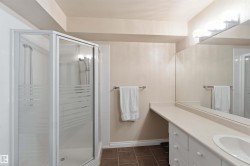 Corner shower enclosure with frosted glass panels, an integrated vanity with a white countertop, an undermount sink, and extensive mirrored wall coverage - 