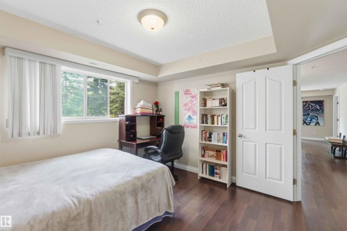 Wood-finish flooring, white paneled door, and a recessed ceiling feature - #104 10221 111 St Nw, Edmonton, AB - Indoor Photo Showing Bedroom