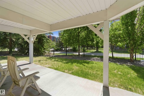 Covered patio with a concrete surface, supported by white structural posts with angled bracing - #104 10221 111 St Nw, Edmonton, AB - Outdoor With Deck Patio Veranda
