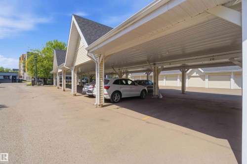 Covered carport parking with corrugated metal roofing and individual garage doors - #104 10221 111 St Nw, Edmonton, AB - 
