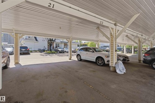 Covered carport featuring concrete flooring, exposed beam construction with corrugated metal roof, and structural support columns - #104 10221 111 St Nw, Edmonton, AB - Indoor Photo Showing Garage
