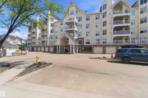 Multi-story residential building featuring balconies, a covered entrance, and ground-level garage doors - #104 10221 111 St Nw, Edmonton, AB - Outdoor With Facade