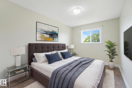 Wall-mounted television, white-framed window, flush-mount ceiling light, and light-colored wall paint - 10234 155 Street Nw, Edmonton, AB - Indoor Photo Showing Bedroom