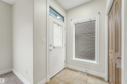 Entryway featuring a white paneled door with decorative glass, transom window, and tile flooring - 