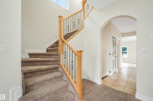 Curved staircase with wood-finish handrails and decorative metal balusters - 10234 155 Street Nw, Edmonton, AB - Indoor Photo Showing Other Room